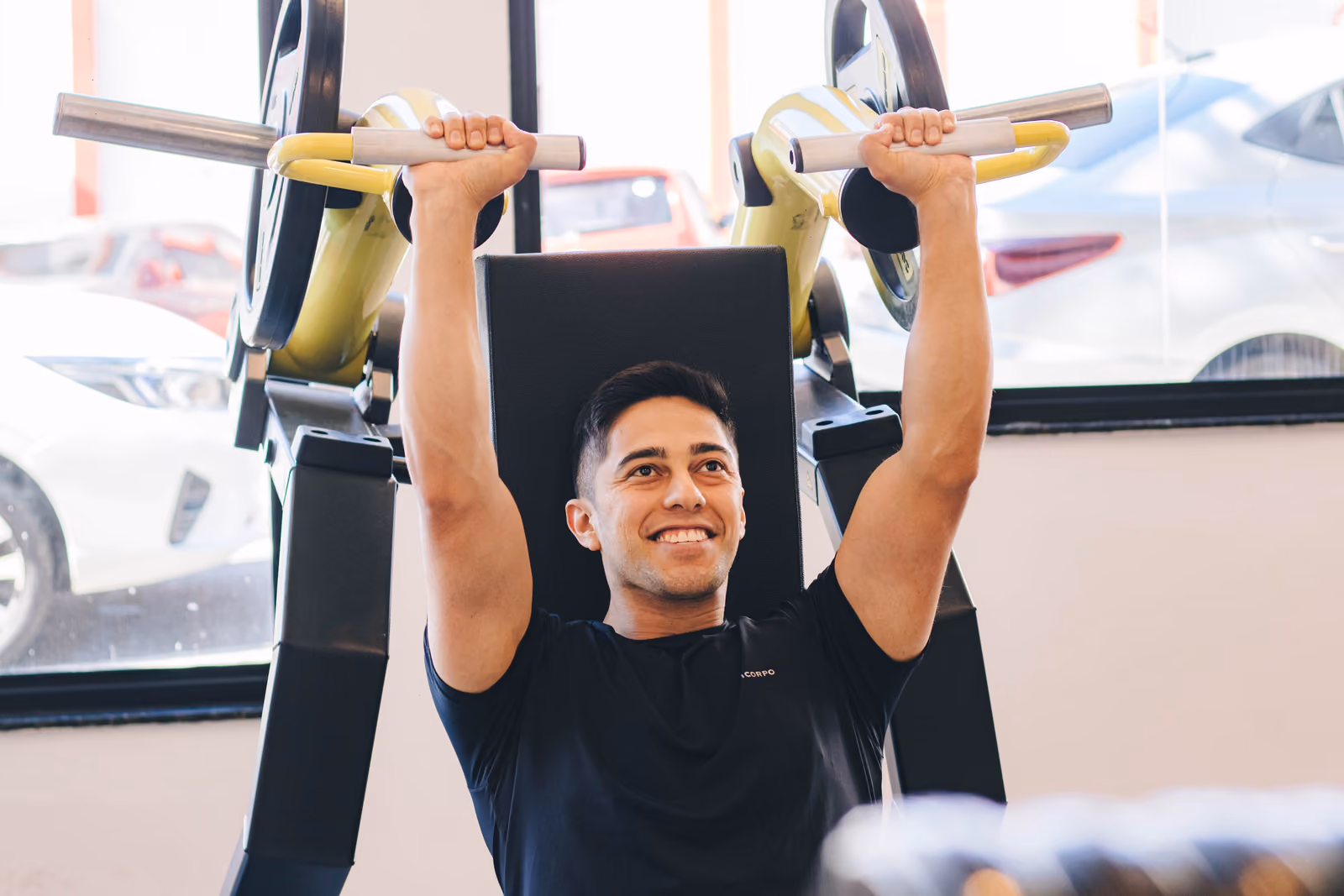 Aluno iniciante treinando e sorrindo na Academia Ajuste